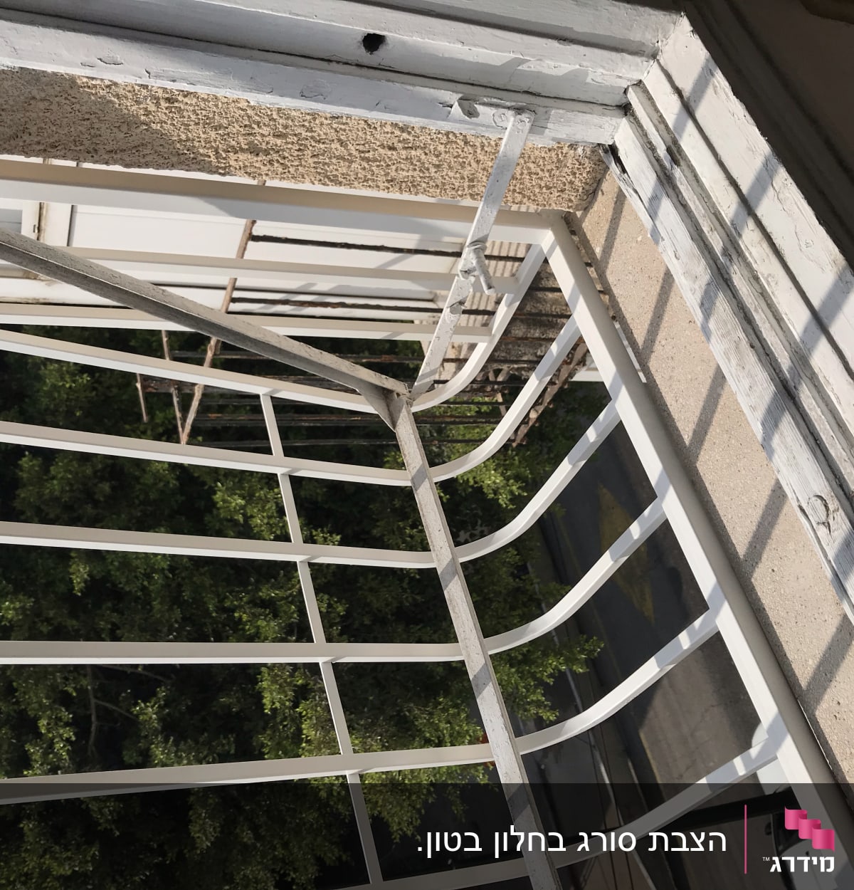 סורגי מתכת לבנים על חלון עם מסגרת עץ